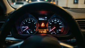 Tableau de bord réaliste d’une voiture la nuit, avec le voyant d’injection moteur allumé et des reflets subtils sur les jauges, ambiance journalistique.